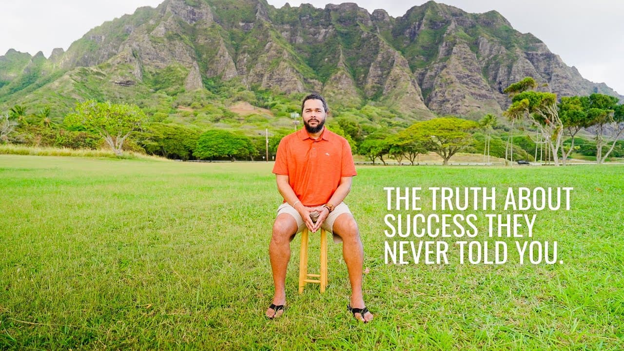 Daniel Molina sitting on a stool in a field below the Ko'olau mountains